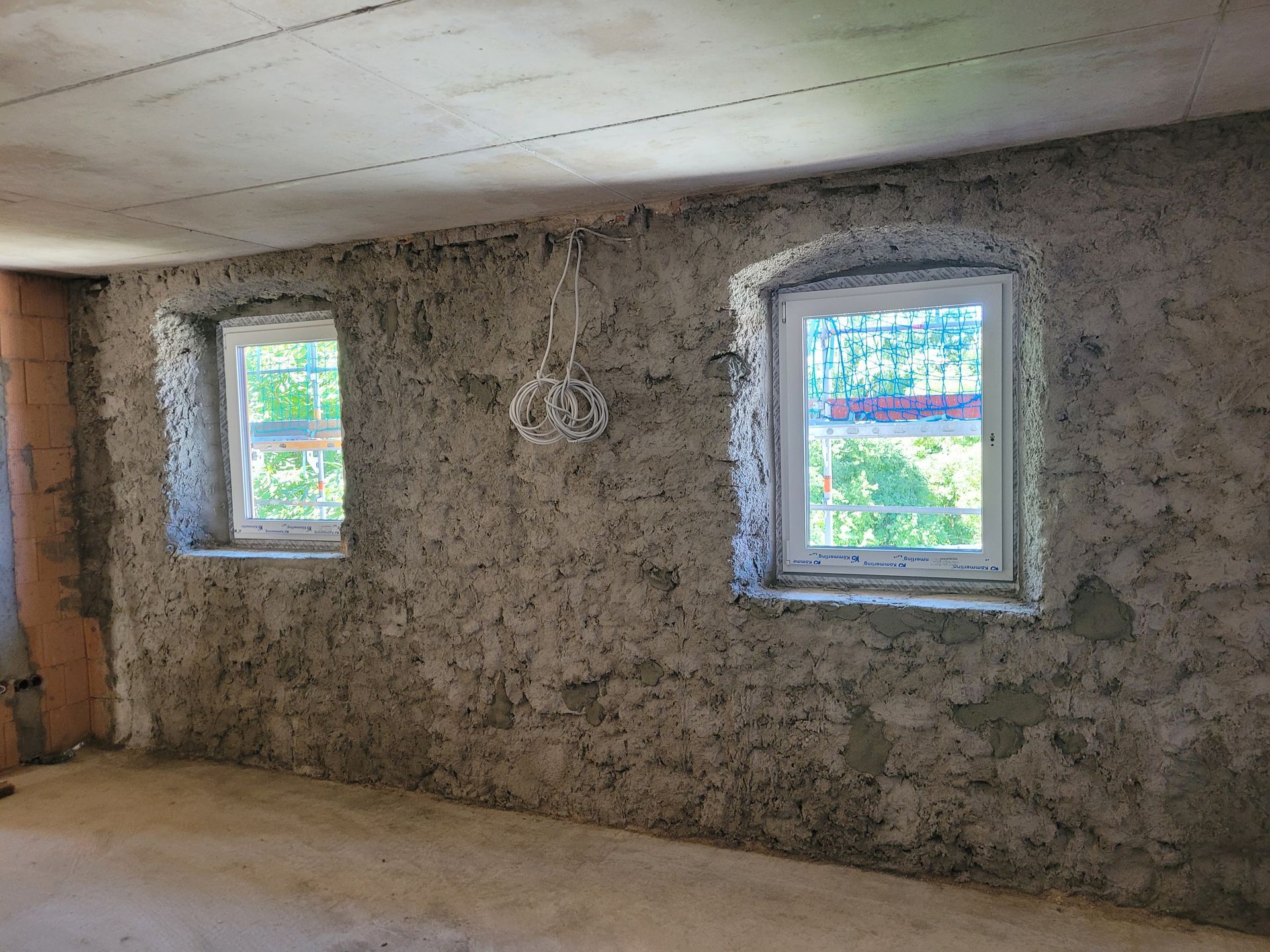 Innenraum mit verputzten Ziegelwänden und zwei Fenstern
