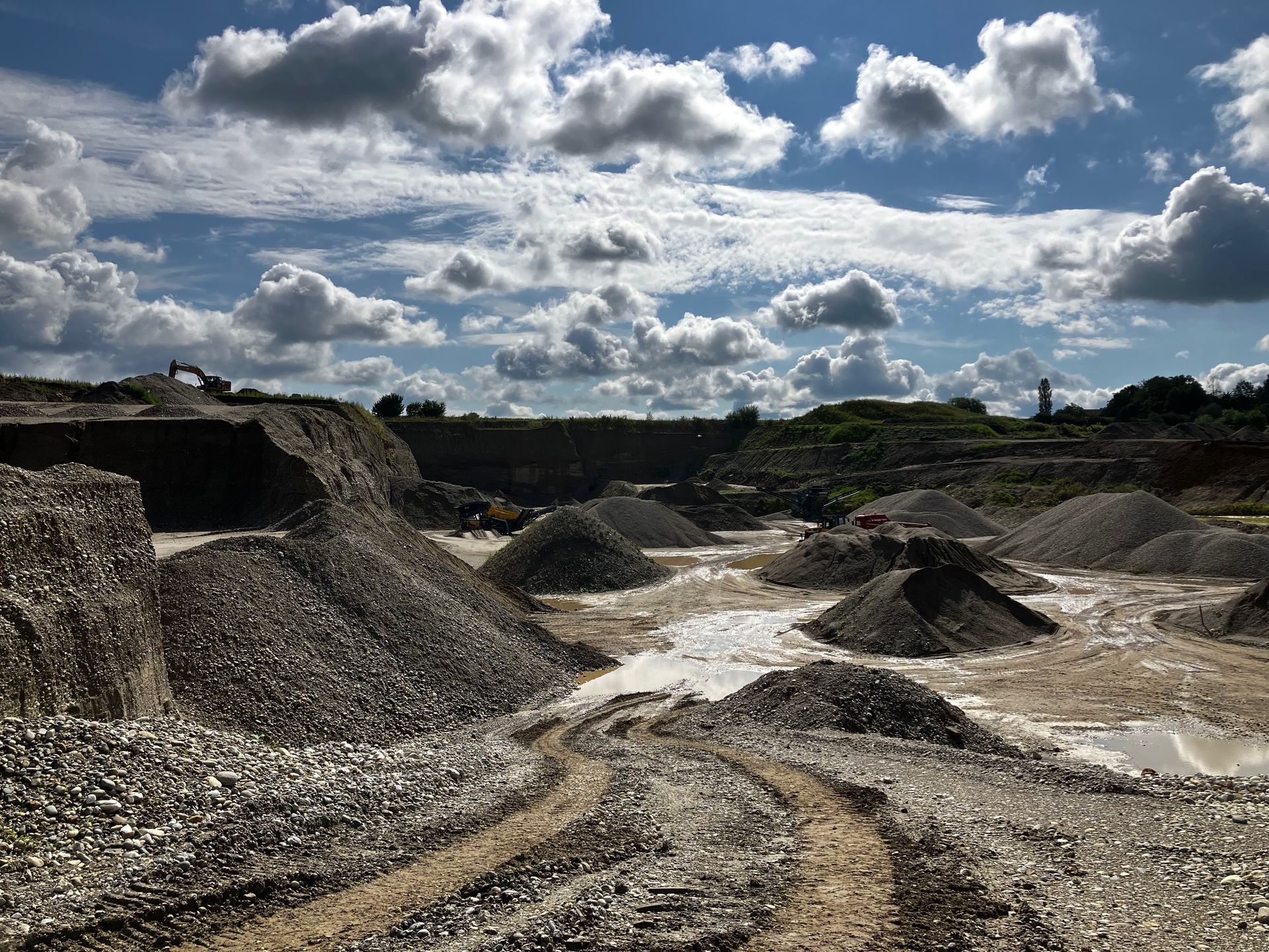 Weitläufige Kiesgrube mit Hügeln und Wolkenhimmel