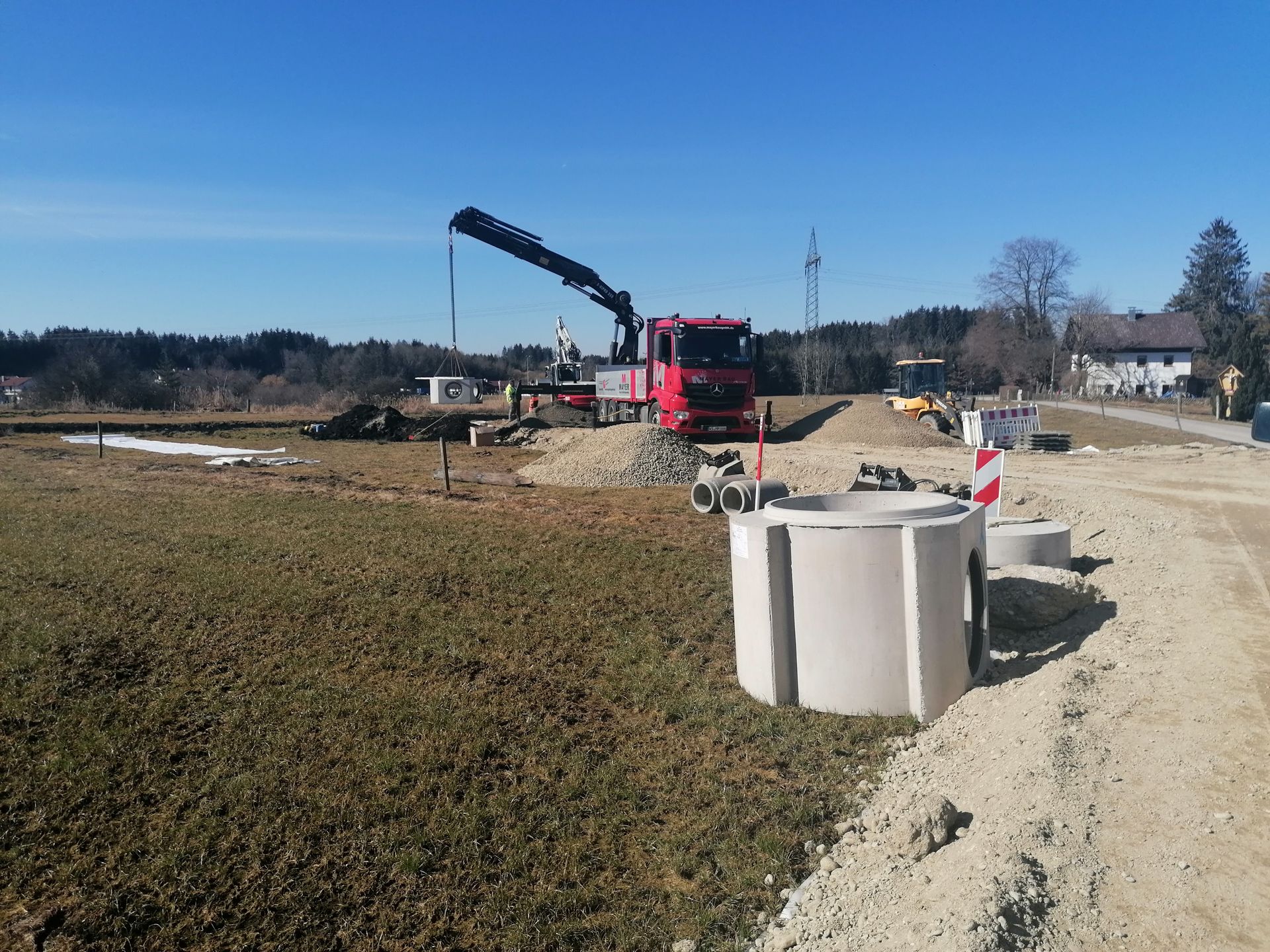Baustelle mit Kran und Betonfertigteilen auf freiem Feld