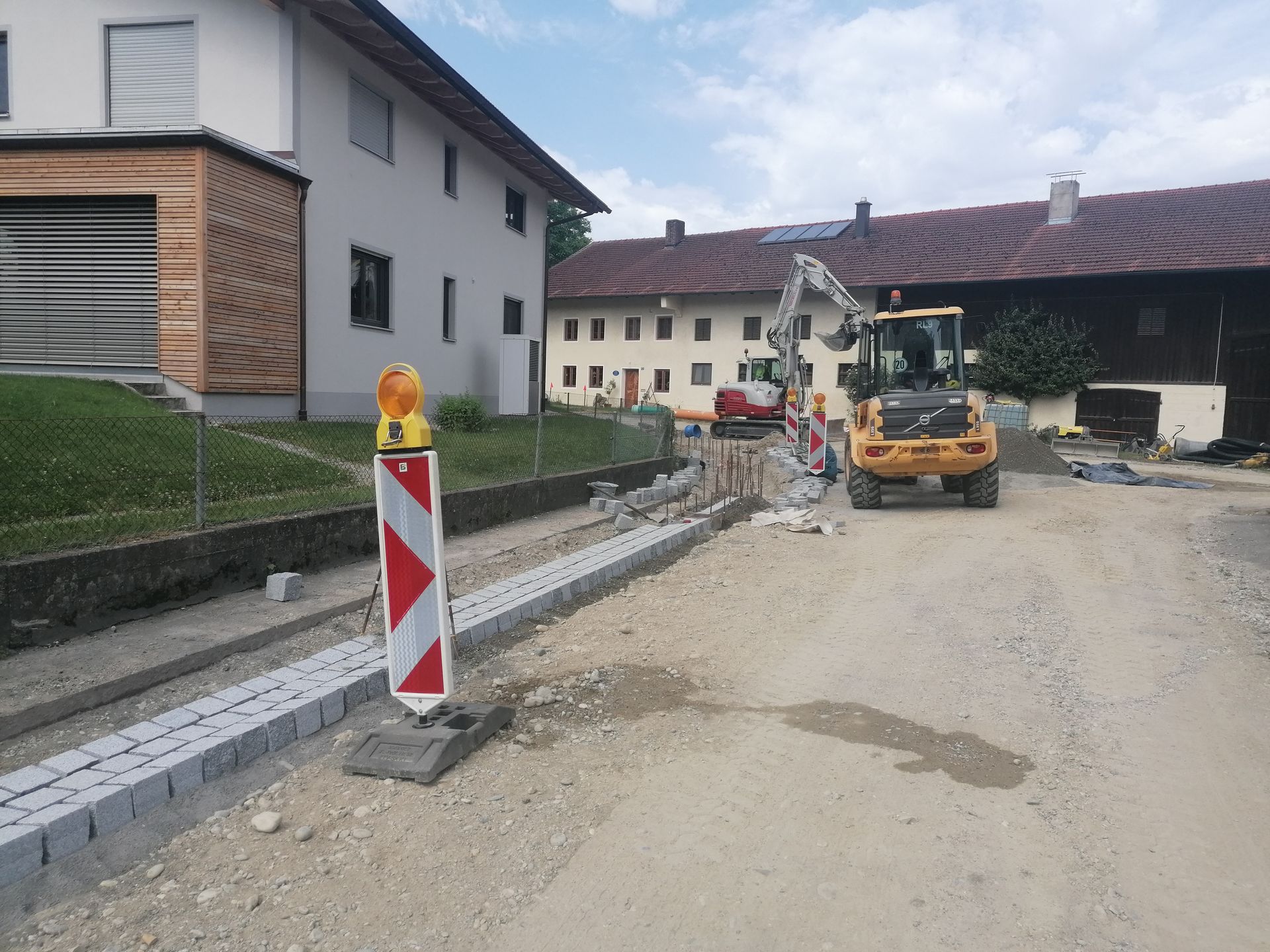 Straßenbauarbeiten mit Absperrung und Bagger im Dorf