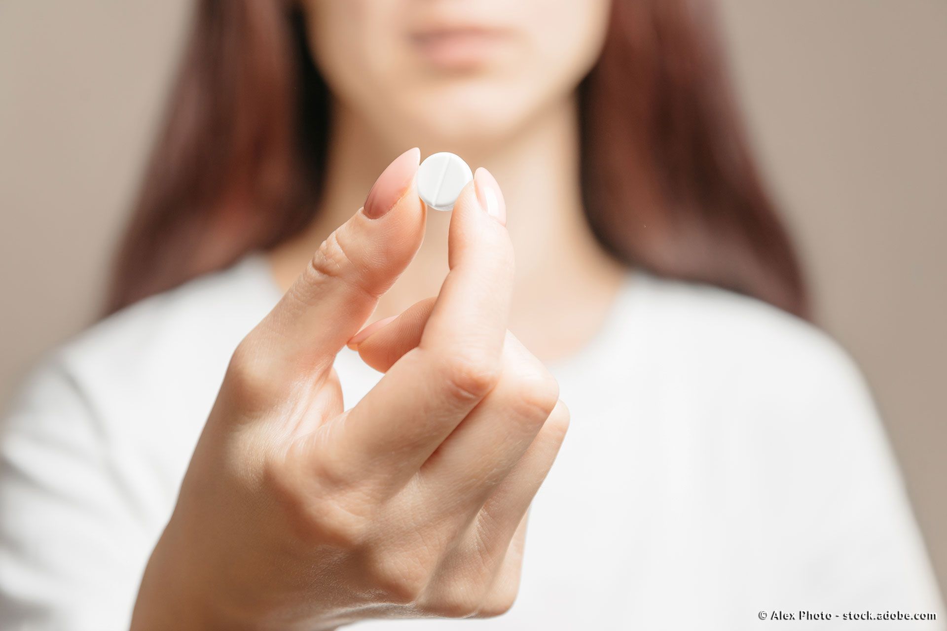eine Frau hält eine weiße Pille in ihrer Hand