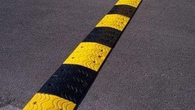 Un reductor de velocidad de color amarillo y negro al costado de una carretera.