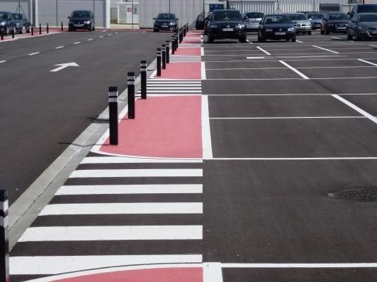 Un estacionamiento con un cruce peatonal rojo y blanco