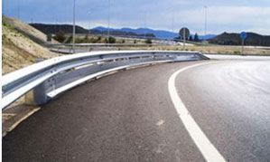 Una carretera con curvas con una barrera de metal al costado.