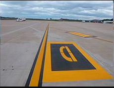 Una pista de aeropuerto con marcas amarillas y negras pintadas en ella.