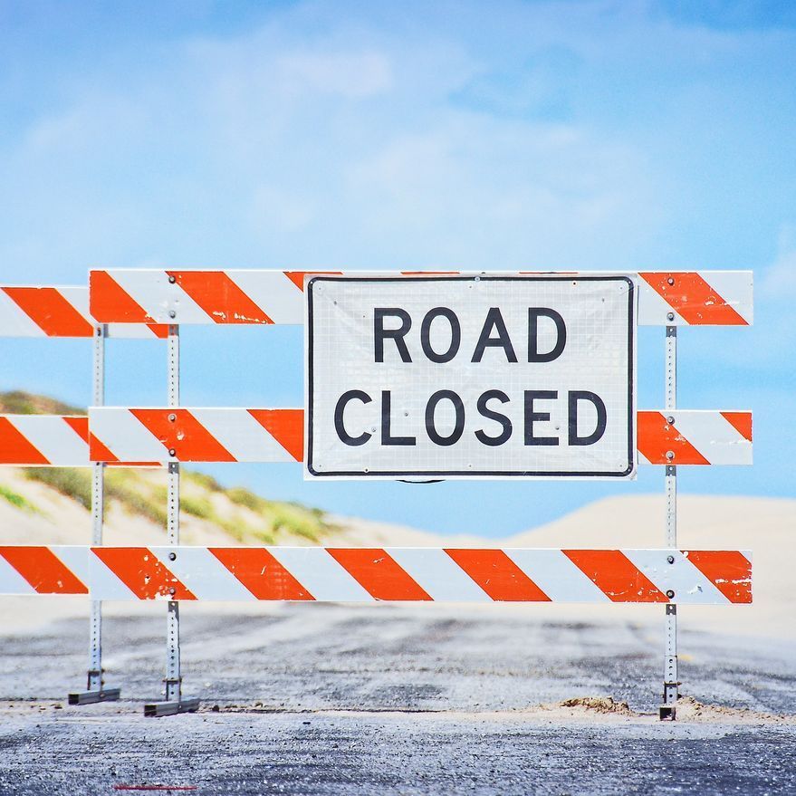 Una señal de carretera cerrada está detrás de una barricada naranja y blanca