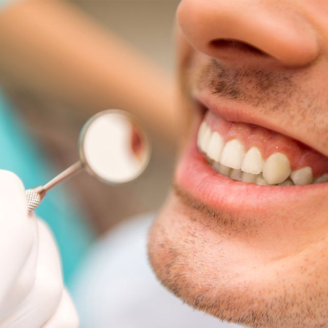Un hombre se está haciendo examinar los dientes por un dentista.