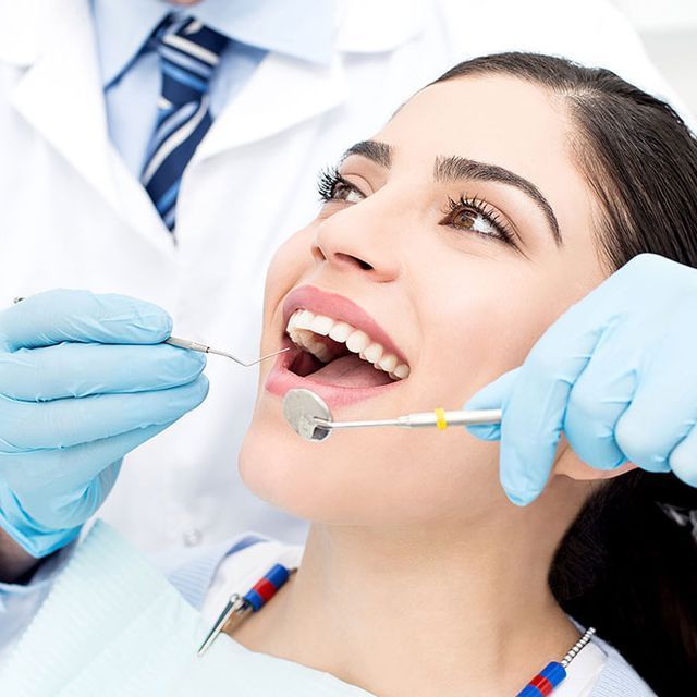 Una mujer se está haciendo examinar los dientes por un dentista.