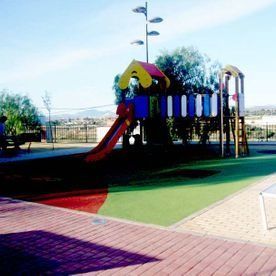 Un colorido parque infantil con tobogán y estructura para trepar en un día soleado en un parque al aire libre.
