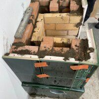 Brick-lined hole in a green metal box with dirt and debris on top, viewed from above