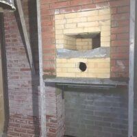 Brick wall with a recessed yellow brick opening and a circular hole, set in a rough industrial interior.