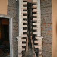 Vertical brick structure with a dark central cavity in an unfinished wall.