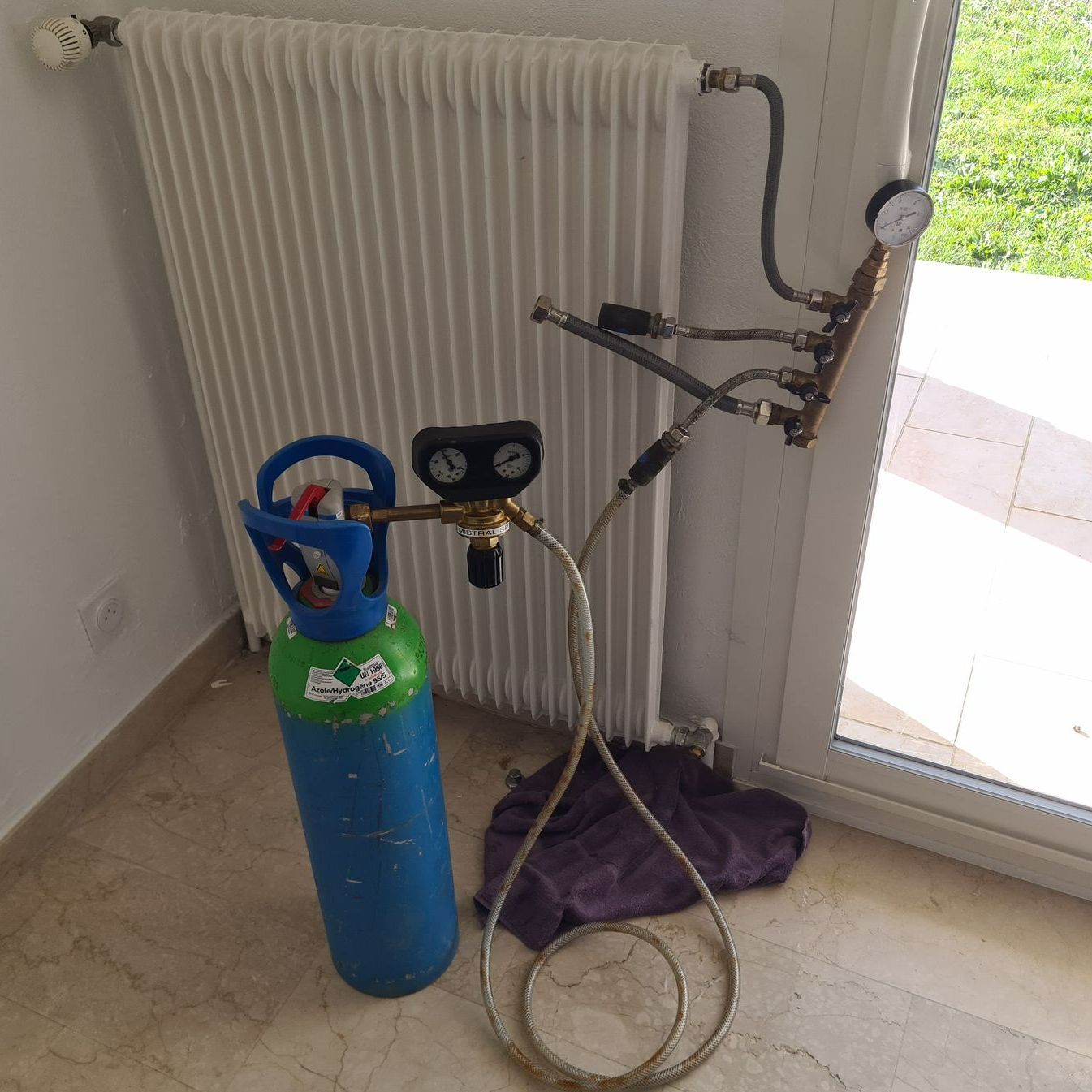 Une bouteille bleue devant un radiateur.