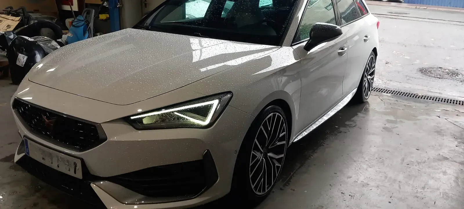 Un coche blanco está aparcado en un garaje al lado de una motocicleta.