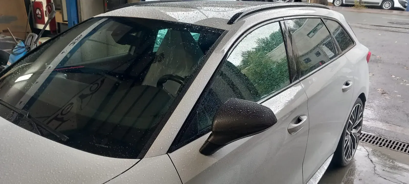 Un coche blanco está aparcado en un estacionamiento bajo la lluvia.