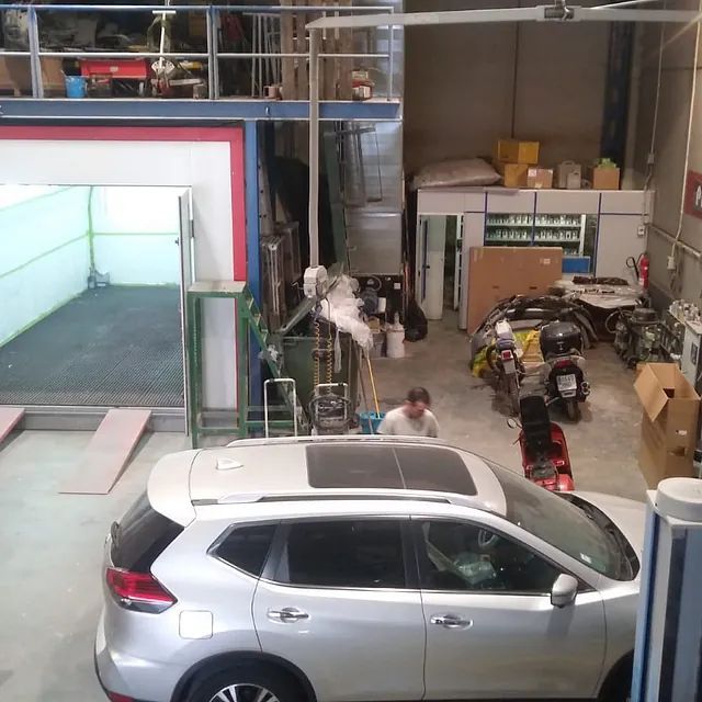 Un todoterreno plateado está estacionado en un garaje al lado de una motocicleta.