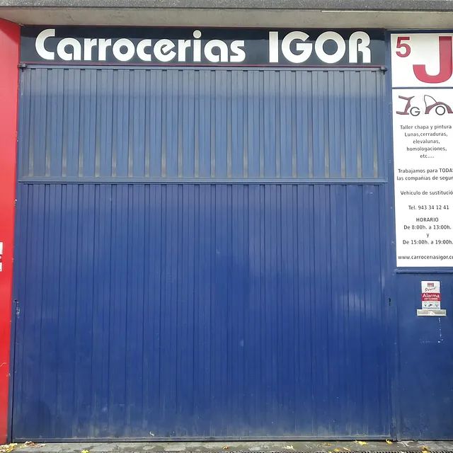 Una puerta de garaje azul con un cartel que dice carrocerias igor