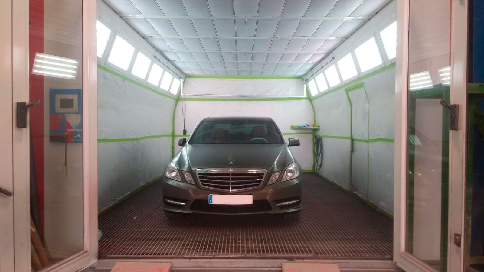 Un coche está aparcado dentro de una cabina de pintura.