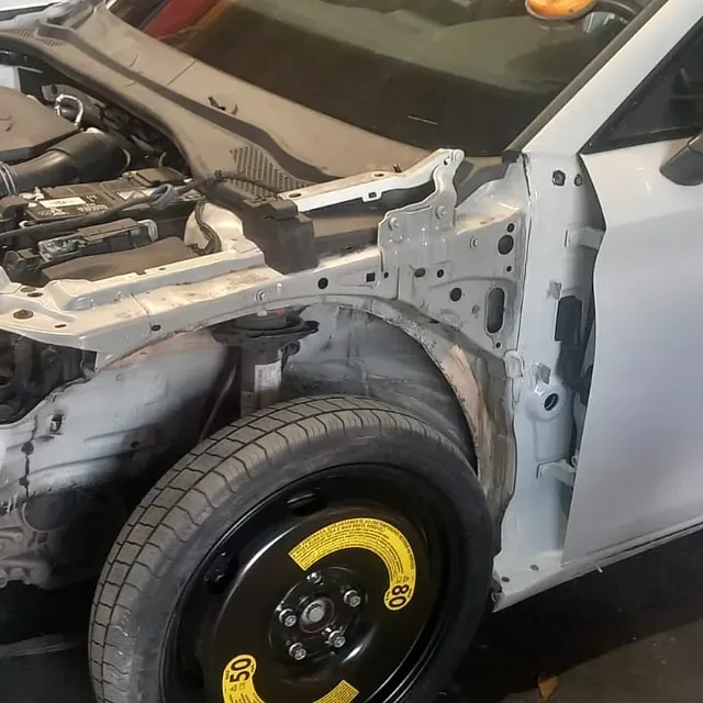 Un coche blanco con el capó levantado y una rueda de repuesto.