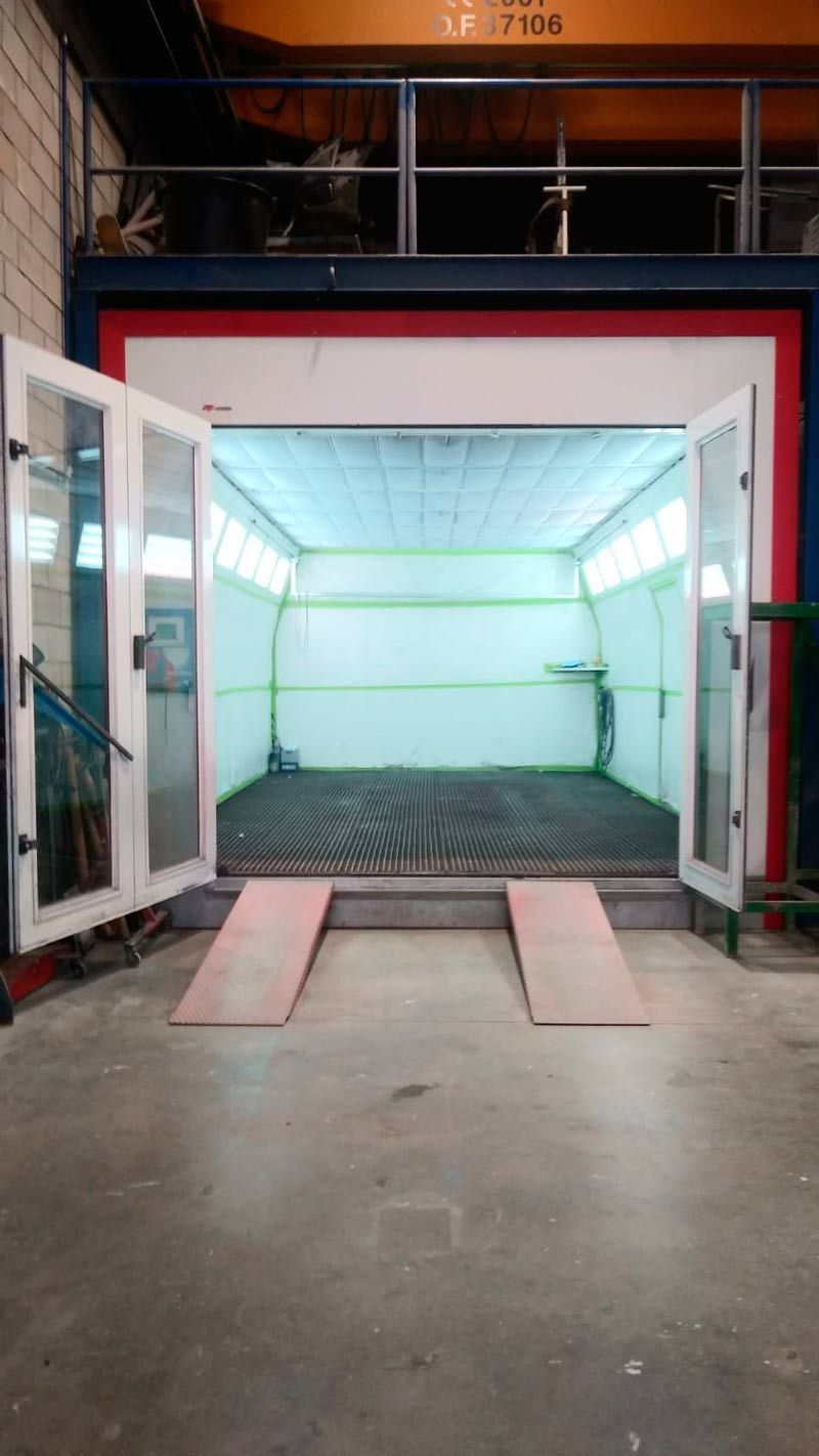 Una cabina de pintura con dos puertas abiertas en un almacén.