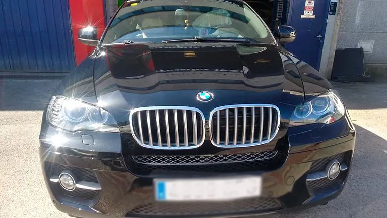 Un BMW X6 negro está estacionado frente a un garaje.