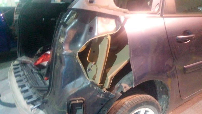 Un coche con un guardabarros dañado está estacionado en un garaje.