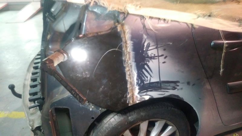 Un coche que ha resultado dañado en un accidente se encuentra estacionado en un estacionamiento.