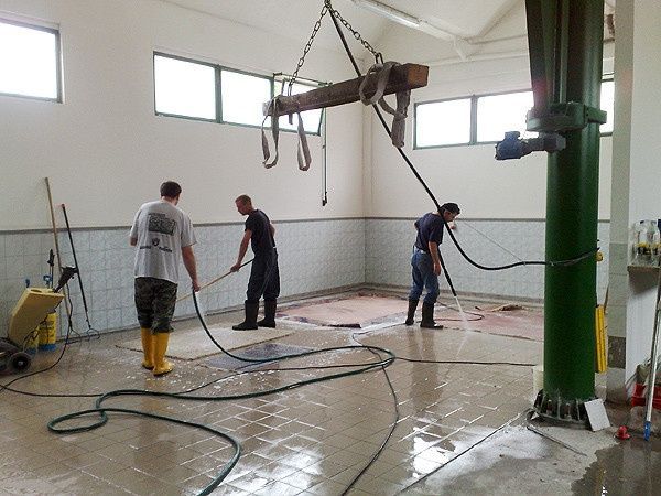 Drei Männer reinigen den Boden eines Gebäudes