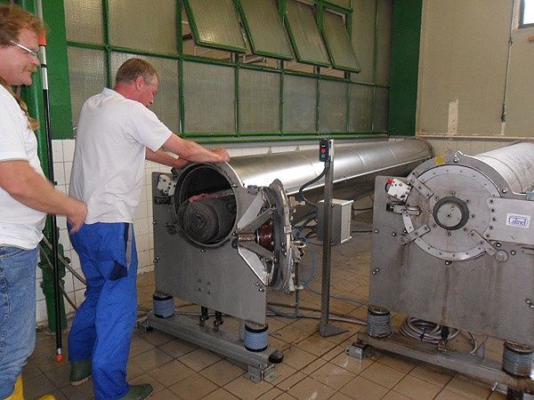 Zwei Männer arbeiten in einer Fabrik an einer Maschine.