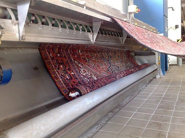 In einer Maschine wird ein Teppich auf ein Förderband gerollt.