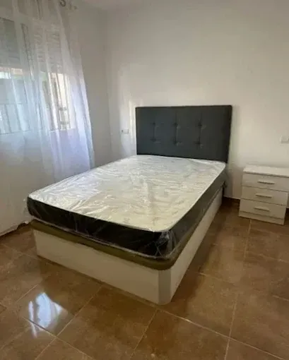 Una cama con cabecero acolchado de color gris oscuro y colchón envuelto