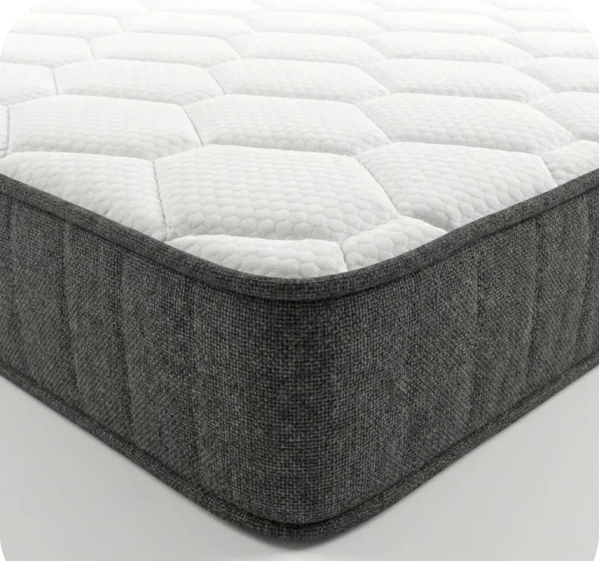 Vista de esquina de un colchón con una superficie superior blanca con estampado hexagonal y laterales de tela gris oscuro.
