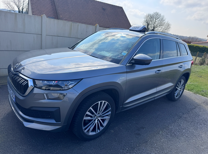 Un SUV Skoda Kodiaq gris garé à l'extérieur, dans une allée, par une journée ensoleillée.