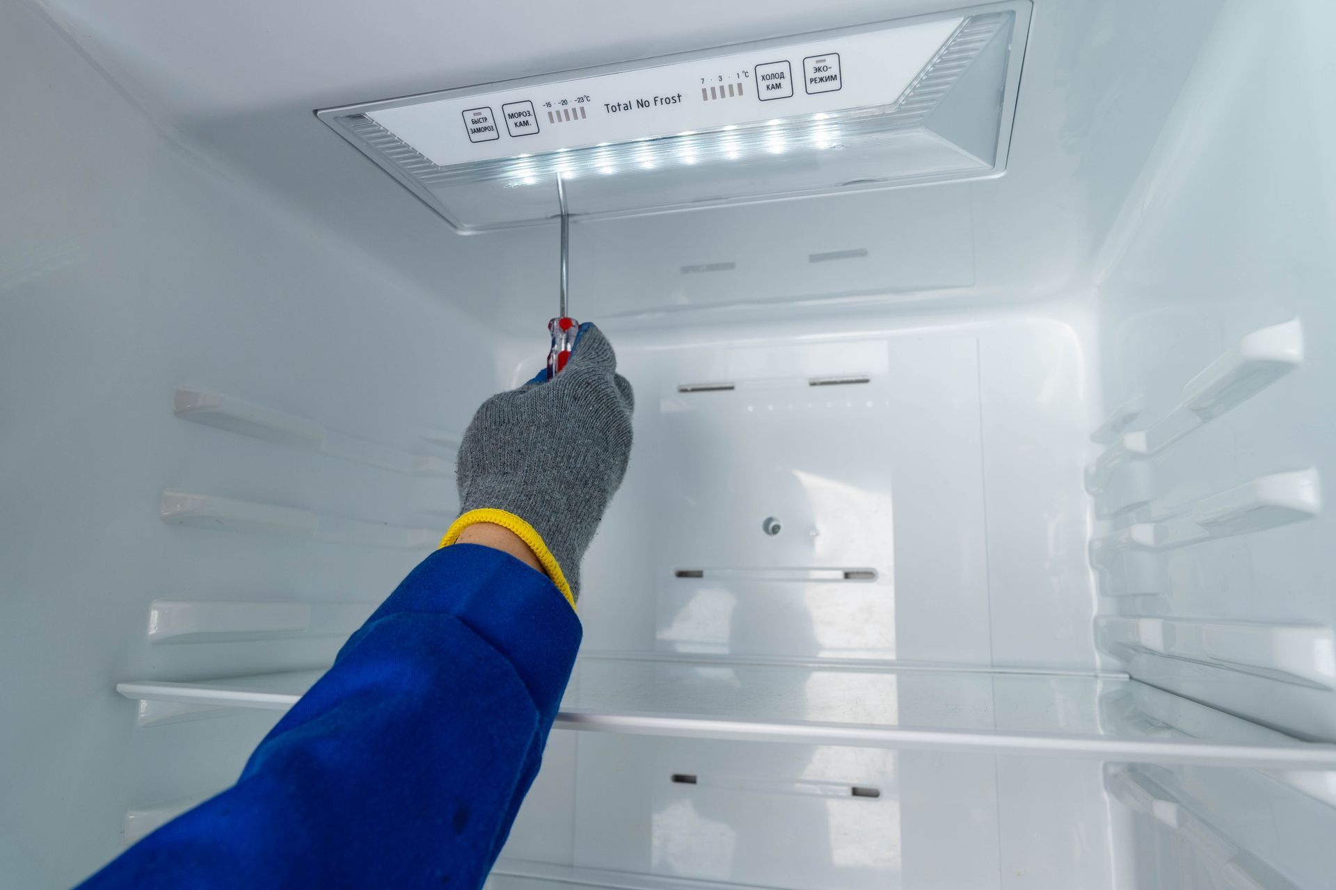 Une main gantée se tend vers le haut pour ajuster un panneau d'aération à l'intérieur d'un compartiment réfrigéré blanc.