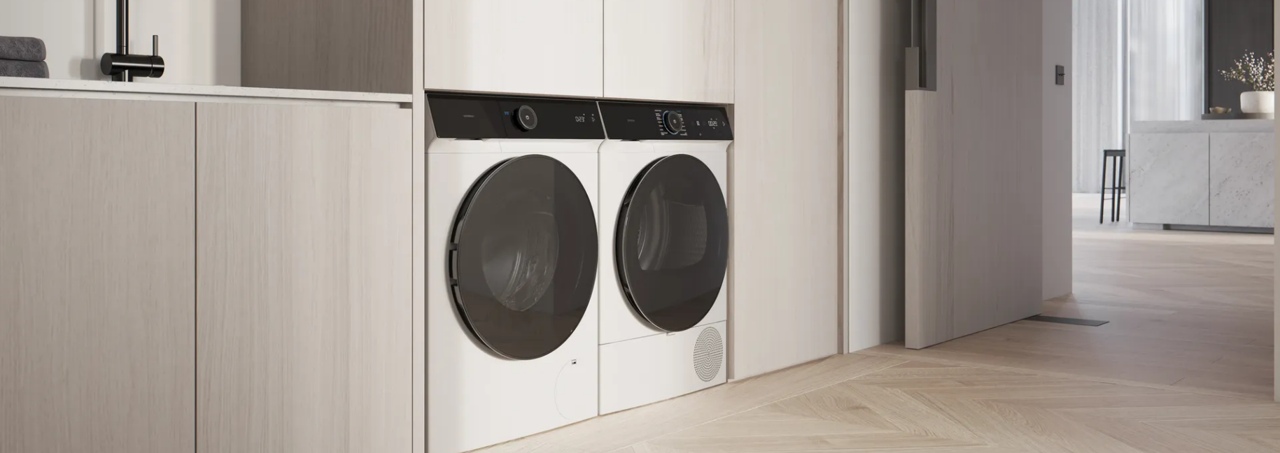 Buanderie avec lave-linge et sèche-linge blancs sous un plan de travail en bois, à côté d'un couloir.