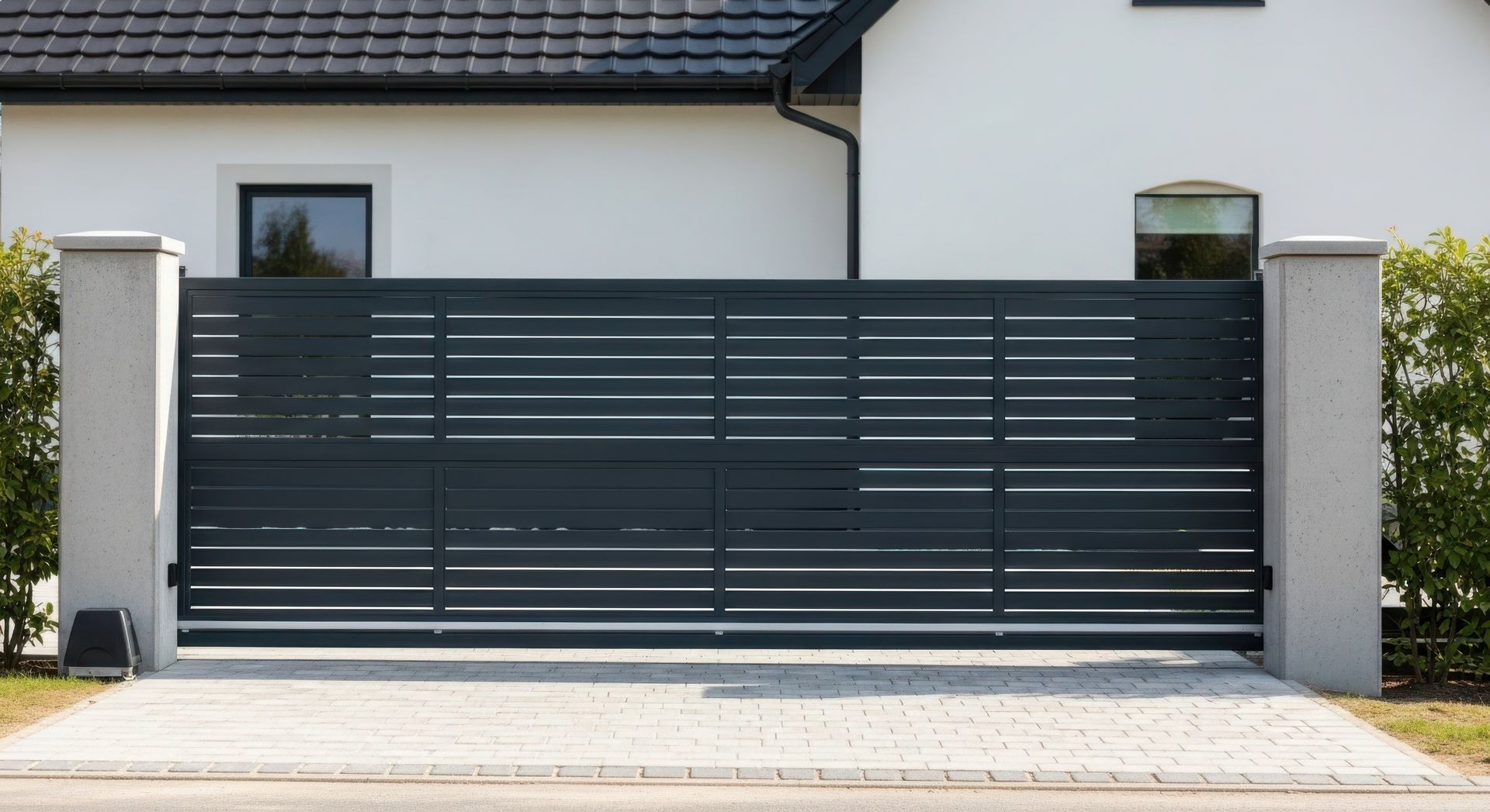 Portail d’allée moderne en métal gris foncé devant une maison de couleur claire
