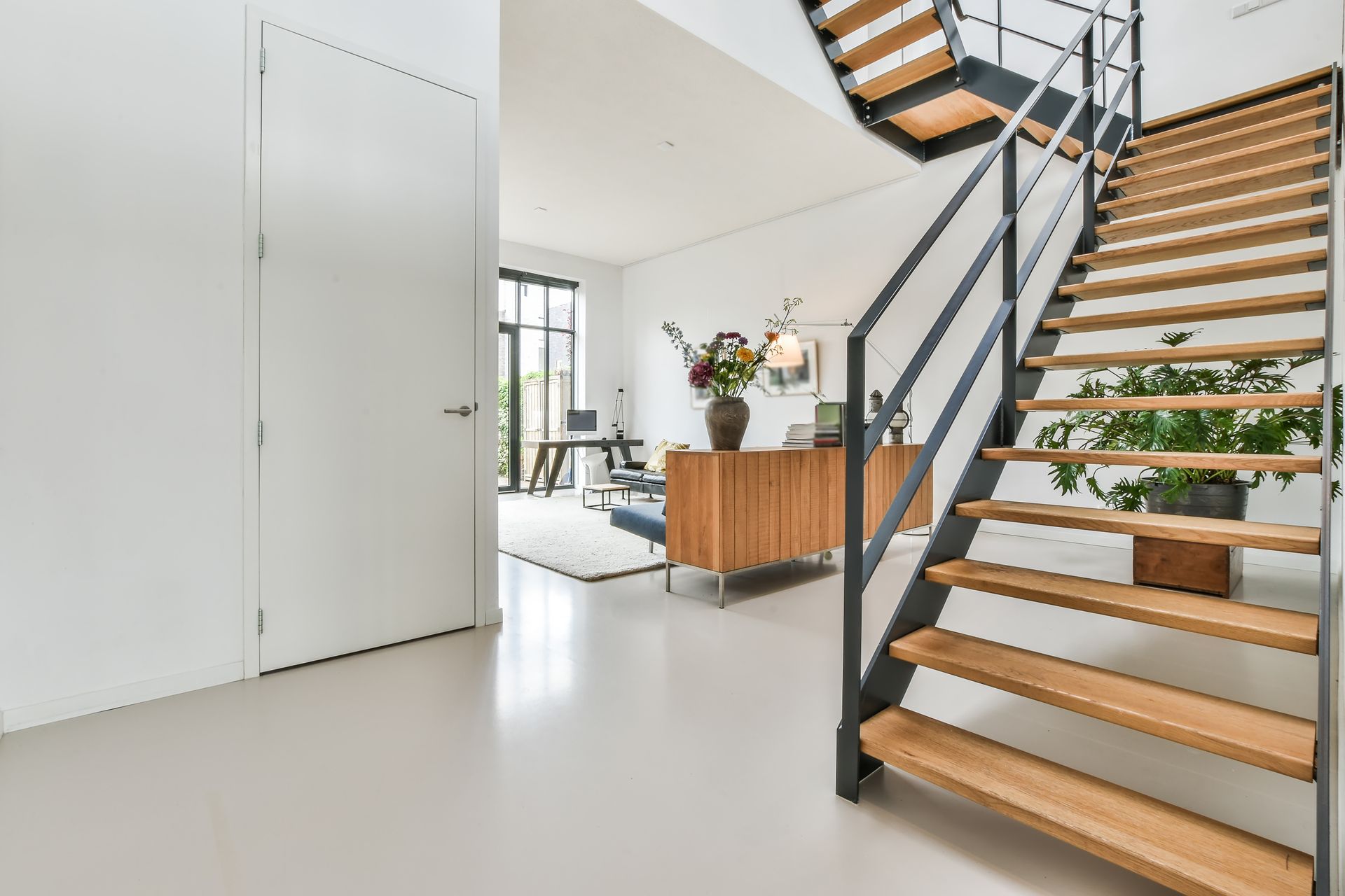 Intérieur moderne et lumineux avec des murs blancs, un escalier et un îlot de cuisine rehaussé de bois