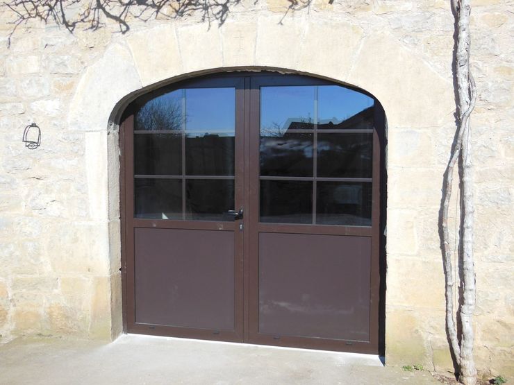 Porte double cintrée marron avec fenêtres, intégrée dans un mur en pierre