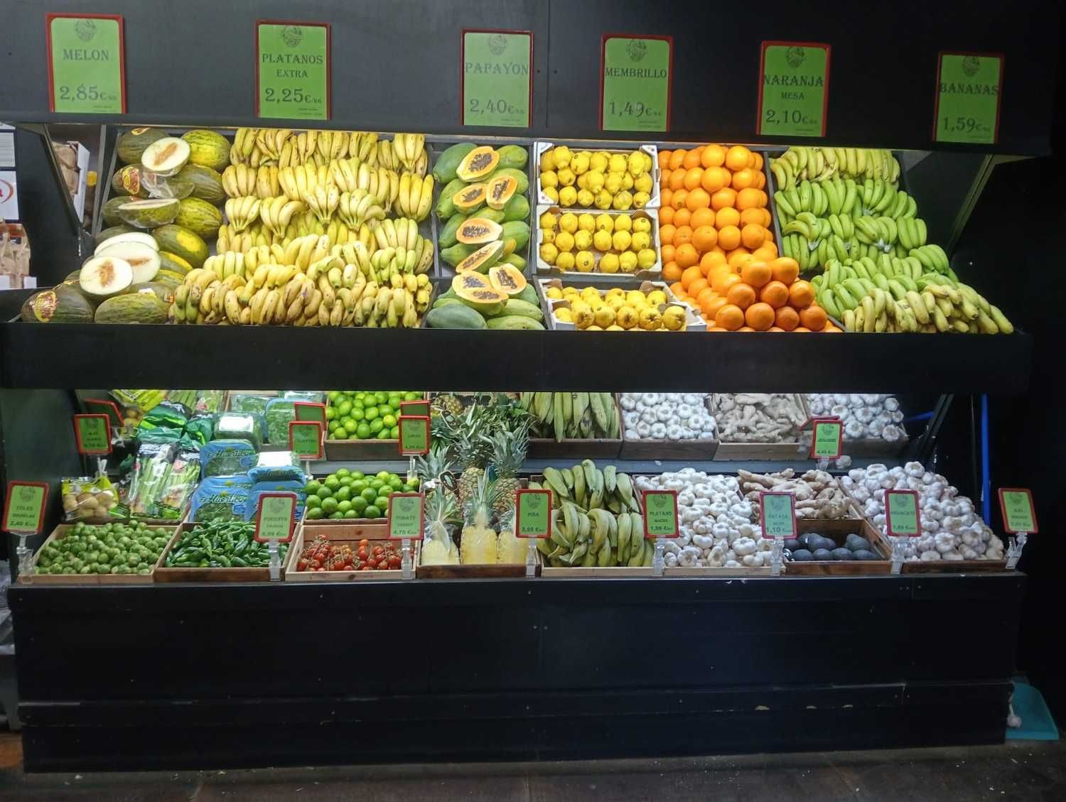 Exhibición de puesto de frutas con diversas frutas de colores: plátanos, papayas, naranjas, limas.