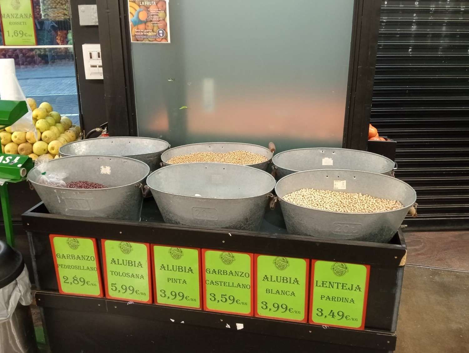 Contenedores metálicos llenos de diversos granos, expuestos a la venta 