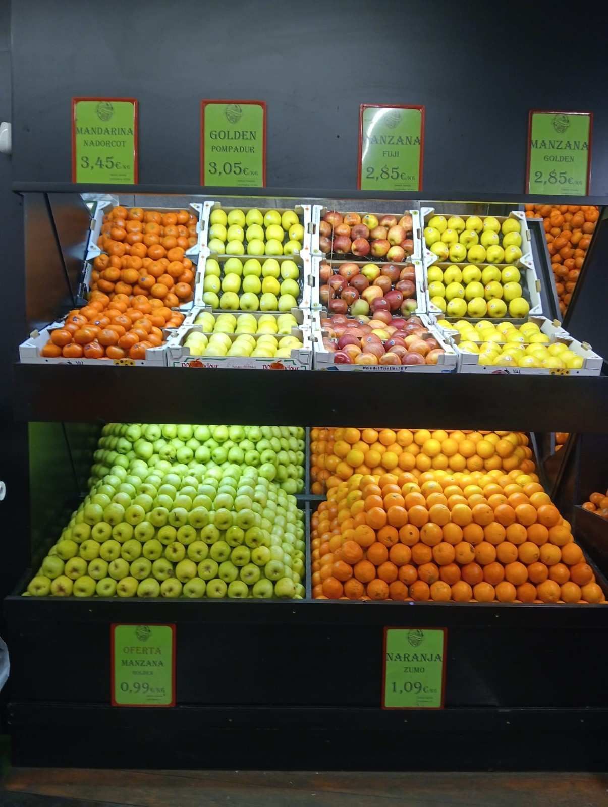 Exhibición de frutas en una tienda, con naranjas y manzanas.