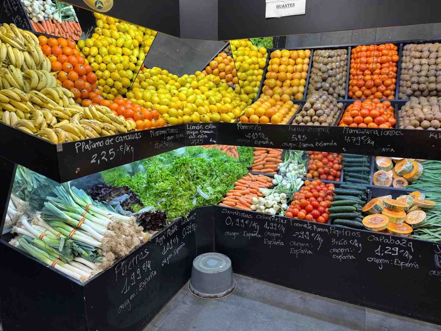 Exhibición de productos en una tienda, mostrando plátanos, naranjas, limones,