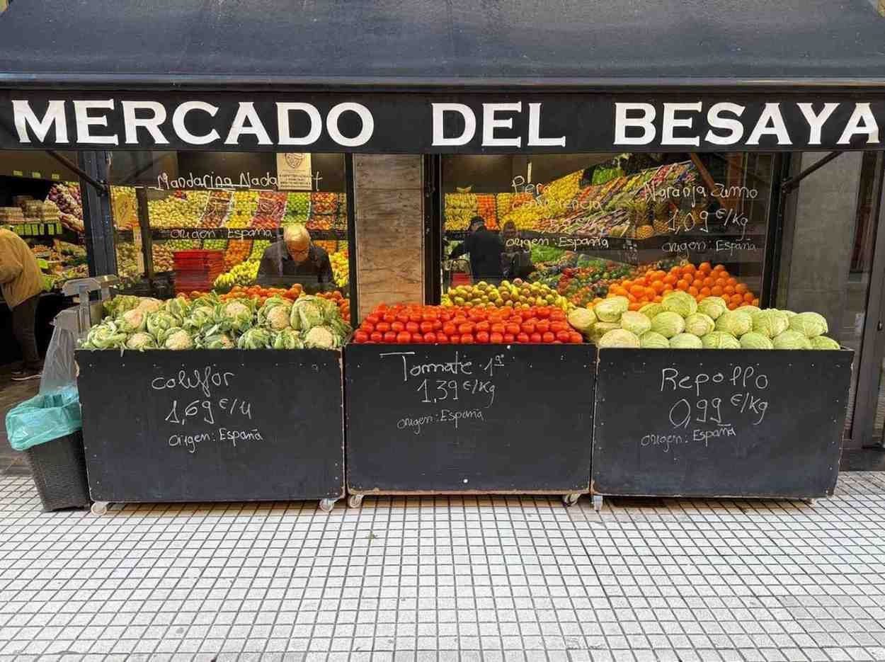 Puesto de productos variados en cajas negras, bajo la marquesina del Mercado Del Besaya.