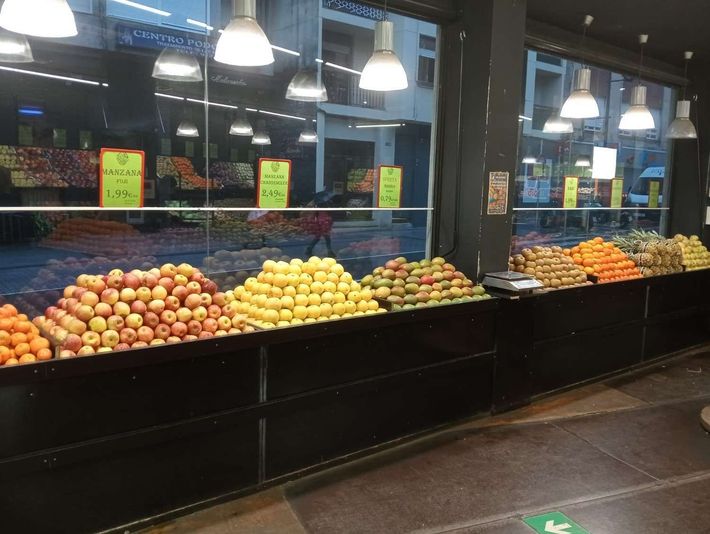 Exhibición de frutas en un supermercado bien iluminado.
