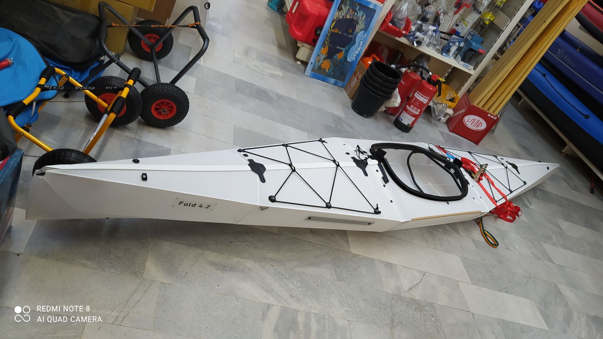 In einem Geschäft steht ein weißes Kajak auf dem Boden.