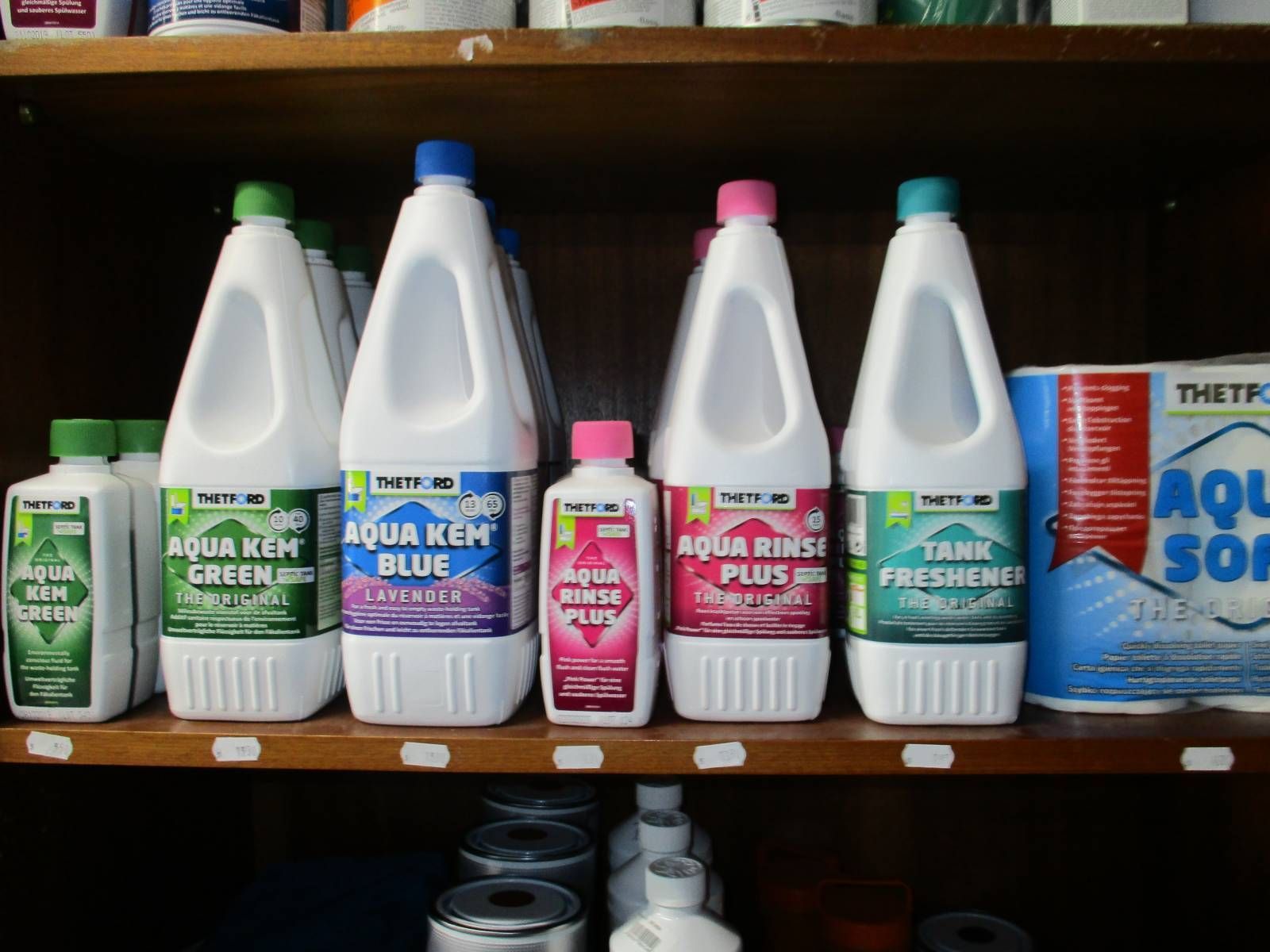 Mehrere Flaschen Bleichmittel stehen auf einem Regal, darunter Aqua Rinse Plus