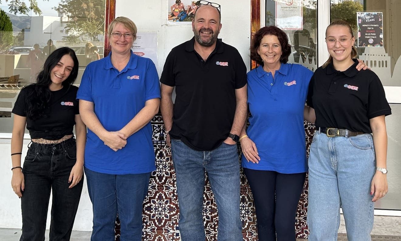 Un grupo de personas vestidas con camisas azules y negras posan para una fotografía.