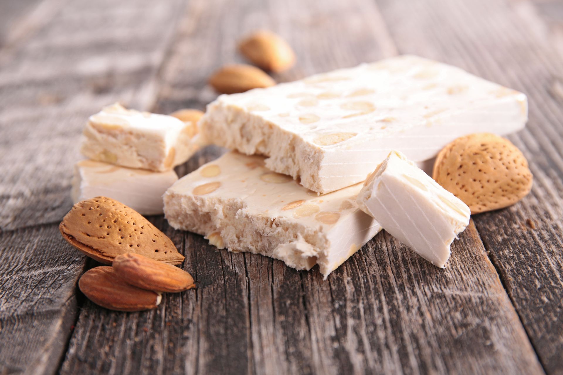 Blocs de nougat aux amandes et biscuits sur une table rustique en bois