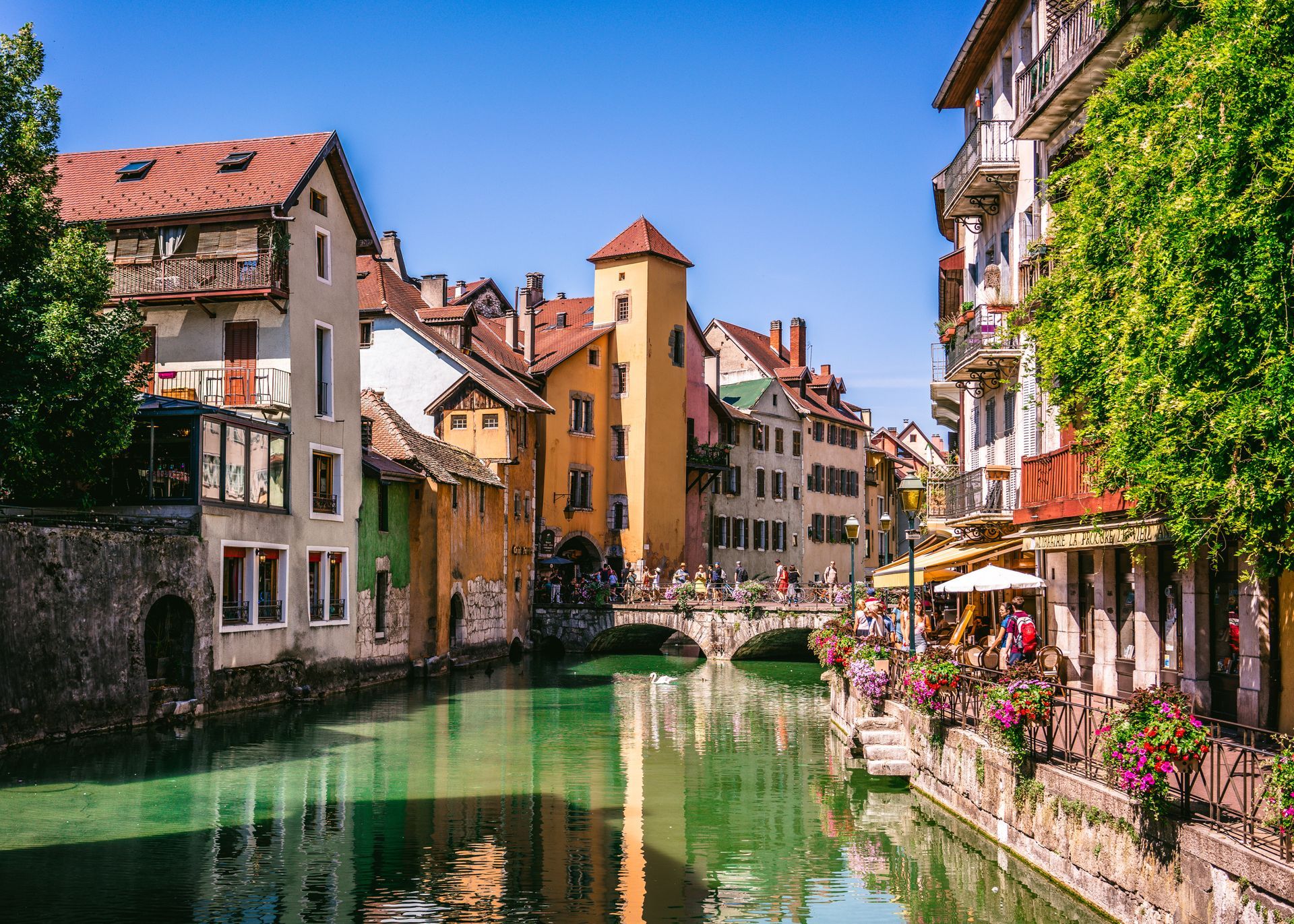 Canal bordé de bâtiments colorés et d'une tour dans la ville d'Annecy.