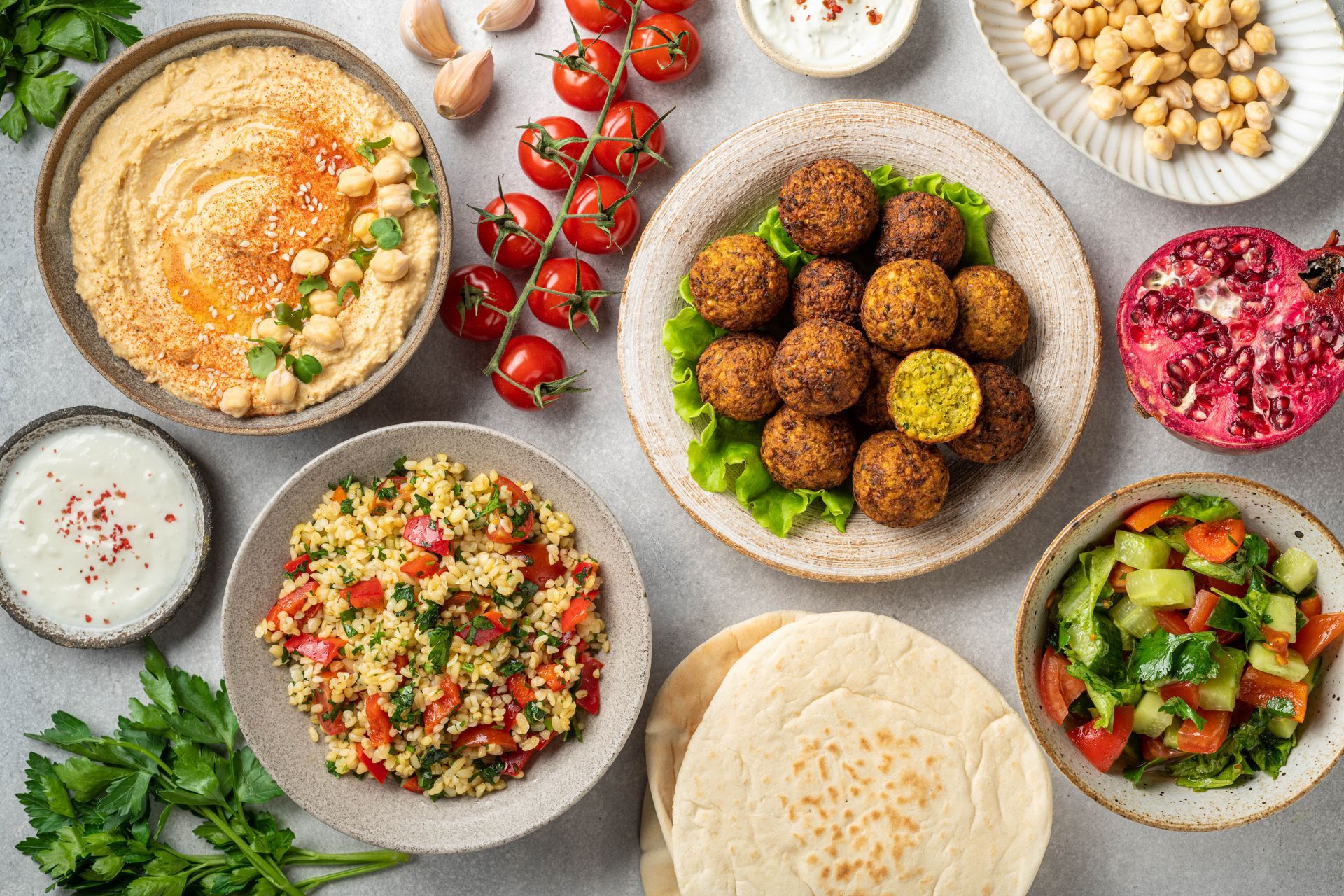 Assortiment de plats du Moyen-Orient sur une table, comprenant du houmous, des falafels, des salades et du pain pita.